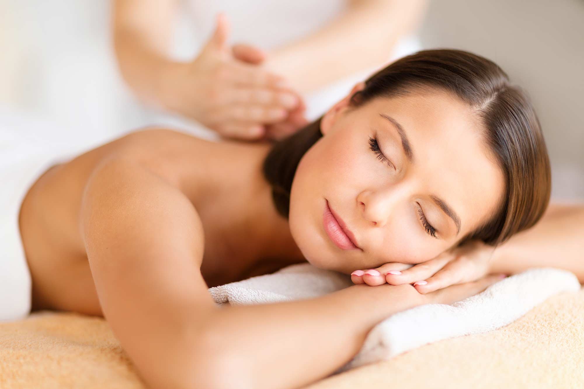 A woman with her eyes closed lying on a massage table to relax after visiting Vancouver attractions.